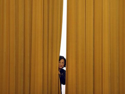 A staff member looks out from a curtain before a press conference following a plenary session of China's National People's Congress (NPC) at the Great Hall of the People in Beijing, Monday, March 19, 2018. China on Monday appointed a former missile force commander as its new defense minister amid lingering concerns over the goals of its rapid military modernization. (AP Photo/Mark Schiefelbein)