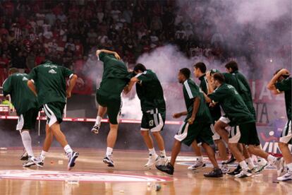 Los jugadores del Panathinaikos huyen de la pista mientras los seguidores del Olympiakos les lanzan petardos y bengalas.