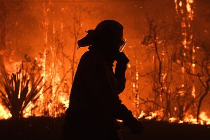 Un oficial del servicio rural de bomberos de Nueva Gales del Sur trabaja en las labores de extinción del fuego en Australia. Gran parte del estado de Nueva Gales del Sur se enfrenta a niveles récord de mala calidad del aire debido a los incendios forestales activos en la zona.
