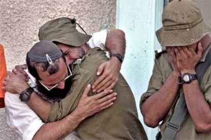 Un colono judío se abraza a un soldado israelí en presencia de otro militar durante el desmantelamiento de una sinagoga en el asentamiento de Nissanit.