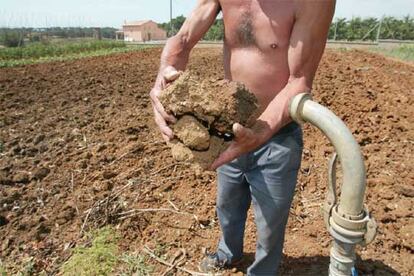 El propietario de una masía en Campllong (Lleida) muestra la tierra de su explotación reseca por la sequía.