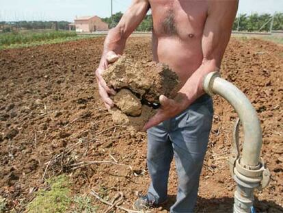 El propietario de una masía en Campllong (Lleida) muestra la tierra de su explotación reseca por la sequía.