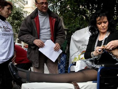 Dolors Carrasquilla cierra el candado con el que permanece encadenada frente al Palau de la Generalitat Valenciana.