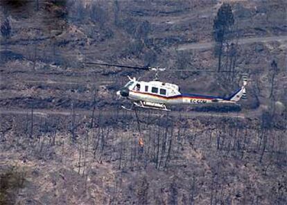 Un helicóptero trabaja en la extinción del fuego en el municipio sevillano de El Madroño.
