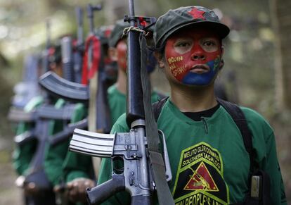 In this photo taken Nov. 23, 2016, members of the New People's Army communist rebels with face painted to conceal their identities, march with their firearms before a news conference held at their guerrilla encampment tucked in the harsh wilderness of the Sierra Madre mountains southeast of Manila, Philippines. Communist guerrillas warn that a peace deal with President Rodrigo Duterte's government is unlikely if he won't end the Philippines' treaty alliance with the United States and resist control by other countries. (AP Photo/Aaron Favila)