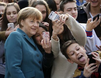 Angela Merkel se hace un 'selfie' junto a un grupo de un niños durante su visita a un colegio en Berlín (Alemania).