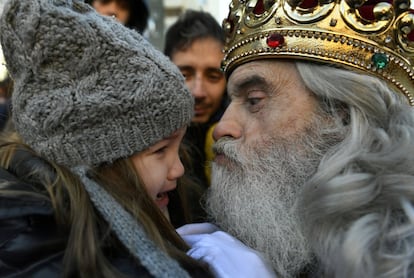 El rey Melchor besa a una niña antes de iniciarse la cabalgata en Gijón (Asturias).