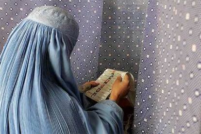 Una mujer vestida con el burka observa la lista de candidatos a la presidencia.
