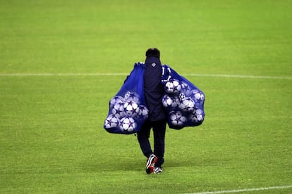 Un asistente del Oporto transporta balones en el césped del Vicente Calderón.