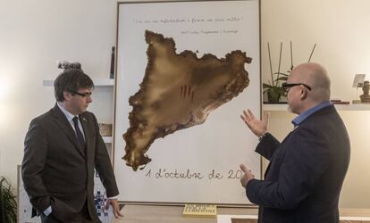 Puigdemont escucha la explicación sobre una de las obras que le han regalado, en Waterloo (Bélgica).