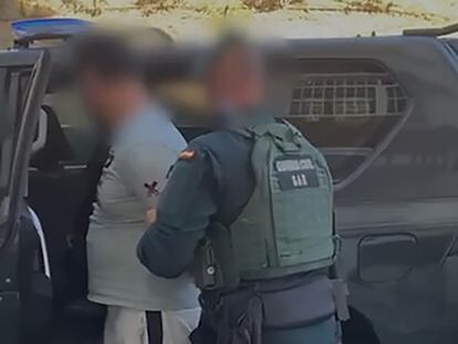 Un agente de la Guardia Civil ayuda a subir al vehículo al arrestado por crear y difundir material yihadista desde Málaga.