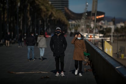 Varias personas con mascarillas pasean por el paseo marítimo de Barcelona.