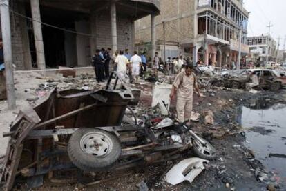 Vecinos de Basora, al sur de Irak, inspeccionan el lugar donde estalló un coche bomba.