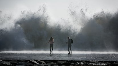 Una pareja corría tras hacerse un selfi en el espigón de la playa de Bogatell, en Barcelona, durante la borrasca 'Gloria', en enero de 2020.