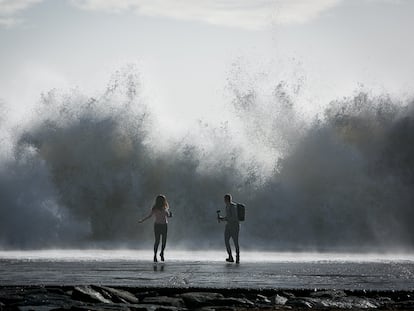 Una pareja corría tras hacerse un selfi en el espigón de la playa de Bogatell, en Barcelona, durante la borrasca 'Gloria', en enero de 2020.