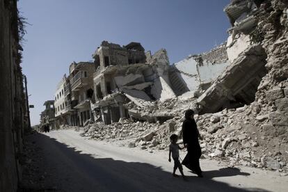 El 3 de septiembre de 2013, una niña y una mujer pasan junto a edificios destruidos de la ciudad de Maarat al-Numaan, provincia de Idlib. Por entonces, el conflicto de la República Árabe Siria, había provocado el desplazamiento interno de unos 4,25 millones de personas. El apoyo de Unicef en el país se centra entonces en programas de agua, saneamiento e higiene, incluido el suministro de agua potable y para uso doméstico para 10 millones de personas; protección infantil, incluidos los servicios de apoyo psicosocial; y nutrición y salud. Si bien muchos niños eran ya refugiados en otros países, más de medio millón de niños no iban a la escuela en Siria. Por lo que el organismo se esforzó también en garantizar la continuidad de la educación.