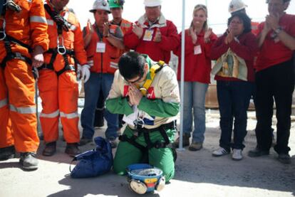 Esteban Rojas, de 44 años, el decimoctavo minero rescatado, reza arrodillado tras salir a la superficie.