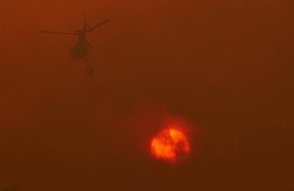 Un helicòpter dels serveis d'extinció treballa per extingir les flames que avancen cap a la localitat de Constante, Lugo.