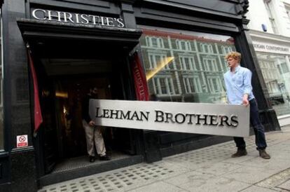 El quebrado grupo financiero Lehman Brothers Holdings venderá en la prestigiosa casa de subastas británica Christie's parte de su colección de arte, que incluye obras de Gerhard Richter y Maya Lin, con la esperanza de poder devolver millones de dólares a sus acreedores. En la imagen, dos personas introducen en Christie's el cartel de su antigua sede, que también saldrá a subasta.