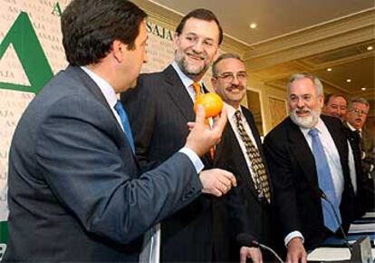 El presidente de la ASAJA, Pedro Barato, ofrece a Rajoy una naranja ante Arias Cañete, esta mañana en Madrid.