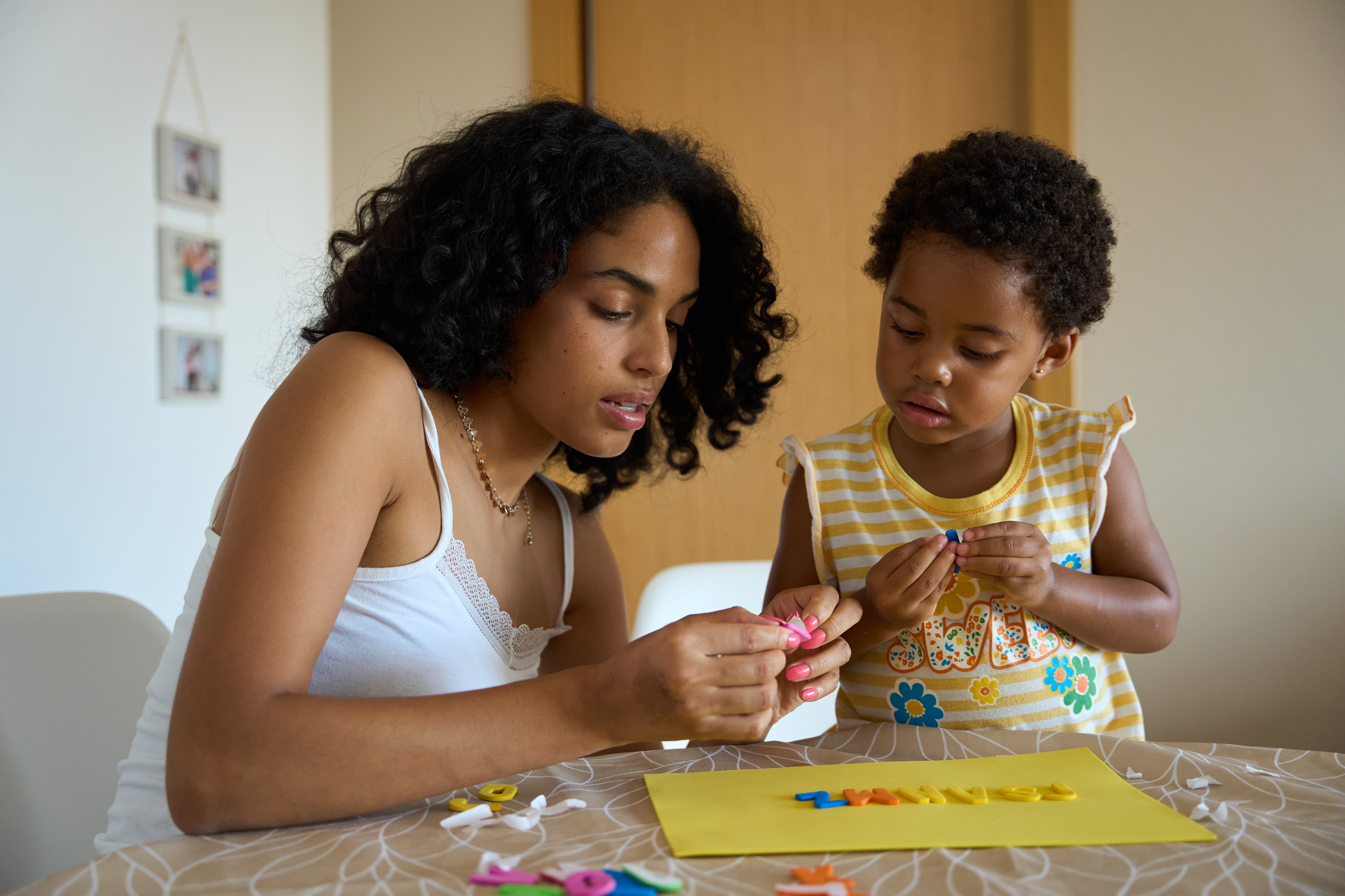 Una madre le enseña el alfabeto a su hija con letras de colores.