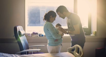 Dos padres miran a su recién nacido.