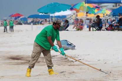 Un operario de limpieza pasa el rastrillo por la playa de Orange Beach en Alabama (EE UU), una de las afectadas por el vertido de petróleo de BP en el golfo de México.