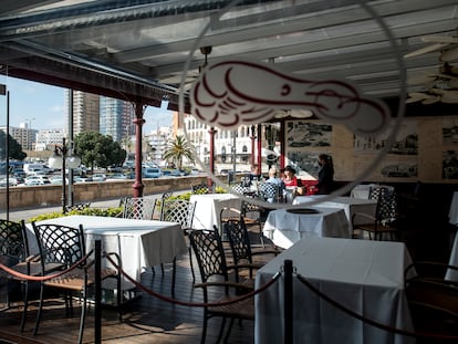 Una camarera atiende la mesa de unos clientes en un restaurante del puerto de Palamós.