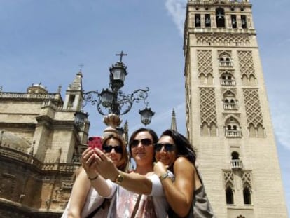 Turistas se fotograf&iacute;an con la Giralda y la Catedral de Sevilla.