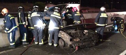 Los bomberos retiran el coche calcinado en la M-40.