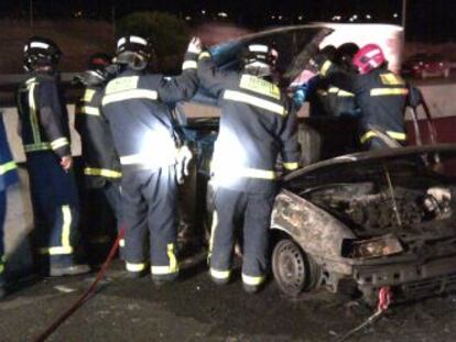 Los bomberos retiran el coche calcinado en la M-40.