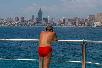 Un hombre contempla la playa de Poniente de Benidorm desde una embarcación.