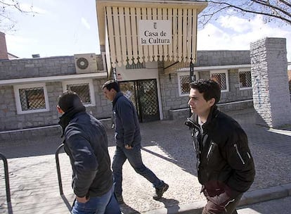 Tres inmigrantes marroquíes pasan delante de la Casa de la Cultura de Fresnedillas de la Oliva.