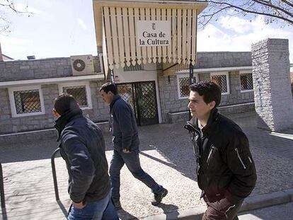 Tres inmigrantes marroquíes pasan delante de la Casa de la Cultura de Fresnedillas de la Oliva.