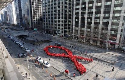 Un grupo de estudiantes surcoreanos posa formando un lazo rojo gigante en una calle de Se&uacute;l.