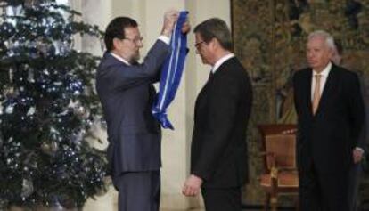 El presidente del Gobierno, Mariano Rajoy (i), impone la Gran Cruz de la Orden del Mérito Civil al ministro de Asuntos Exteriores de Alemania, Guido Westerwelle, en un acto celebrado en el Palacio de la Moncloa al que también ha asistido el jefe de la diplomacia española, José Manuel García-Margallo (d).
