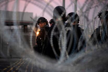 Los oficiales del Equipo de Respuesta Especial (SRT) de Aduanas y Protección Fronteriza (CBP), vistos a través de un cable de concertina en el Puerto de Entrada San Ysidro, donde se ha cerrado el cruce de la frontera terrestre al tráfico temporalmente, en Tijuana (México).