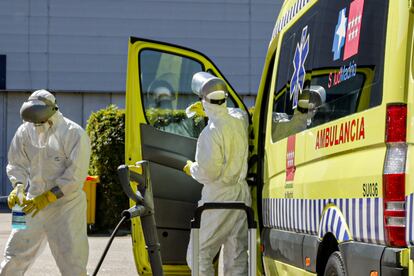 Dos bomberos de la Comunidad de Madrid limpian una ambulancia del SAMUR utilizada para trasladar enfermos de coronavirus en el punto de desinfección cercano al hospital de campaña montado en el recinto madrileño de IFEMA, en Madrid, el 3 de abril de 2020.