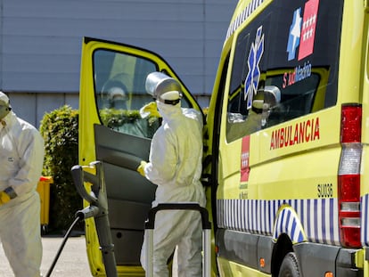 Dos bomberos de la Comunidad de Madrid limpian una ambulancia del SAMUR utilizada para trasladar enfermos de coronavirus en el punto de desinfección cercano al hospital de campaña montado en el recinto madrileño de IFEMA, en Madrid, el 3 de abril de 2020.