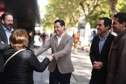 El candidato del PP a la presidencia de la Junta de Andalucía, Juanma Moreno (centro), saluda a una mujer durante un paseo en Córdoba, el 16 de noviembre de 2018.