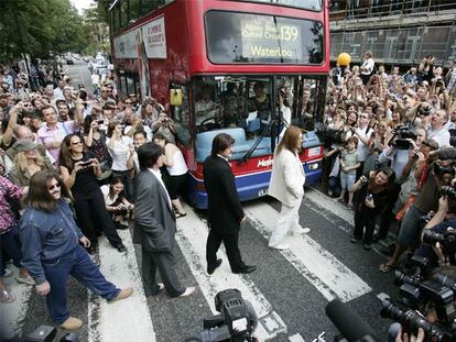 Cuatro imitadores de los Beatles cruzan el paso de cebra de Abbey Road en Londres rodeados de seguidores del grupo.