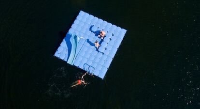 Tres bañistas disfrutan de una plataforma de natación en un piscina natural en Hamburgo (Alemania).