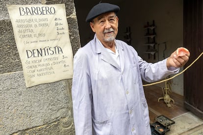 El vecino que actúa como barbero y dentista en la feria de Orhipean posa con una dentadura en la mano.
