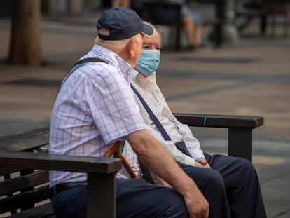 Dos hombres, uno protegido con mascarilla, charlan sentados en un banco este miércoles en Vitoria.