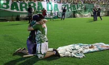 Dos aficionados se abrazan en el homenaje al Chapecoense en el estadio Conda (Brasil).