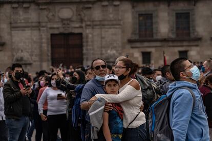 Una mujer y un hombre abrazan a un chico, en la explanada del Zócalo, en Ciudad de México.