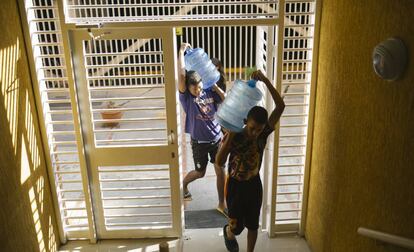 Dos jóvenes suben agua a sus casas.