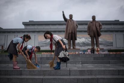 Estudiantes limpian los escalones frente a las estatuas de los líderes norcoreanos, Kim Il-Sung y Kim Jong-Il en Pyongyang, el 27 de julio de 2017.