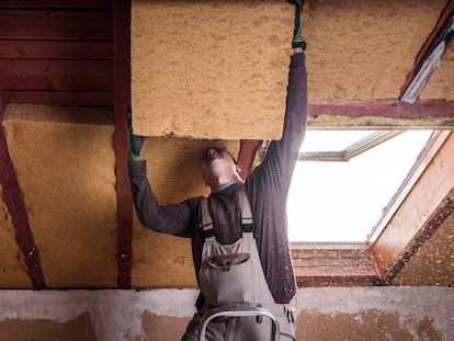 Un trabajador colocaba aislamiento en el techo de una vivienda.