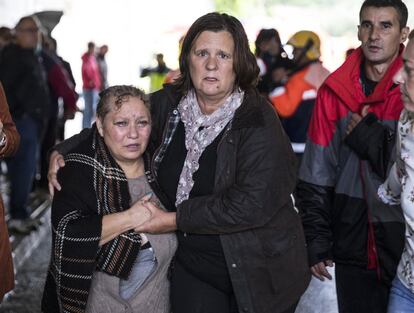 Vecinas de Ontinyent (Valencia) tras ser desalojados por personal de emergencias tras las fuertes lluvias caídas en la localidad, este jueves. La gota fría está ocasionando estragos en algunos municipios en el área mediterránea.